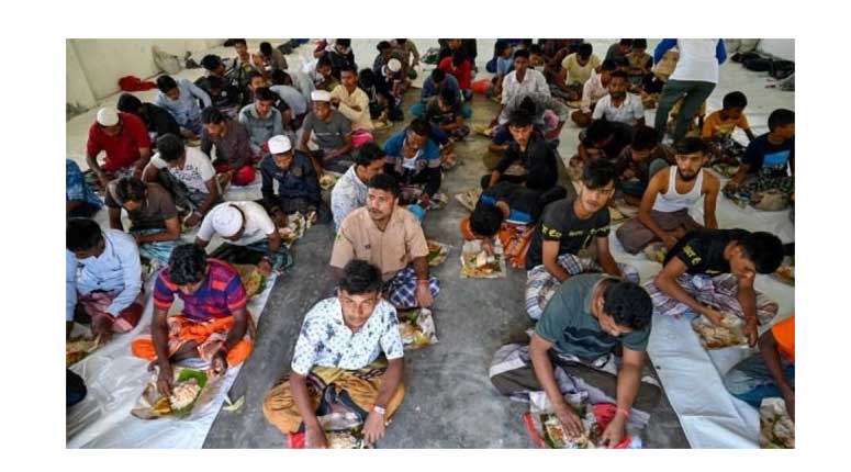 Rohingya refugees eat breakfast at a temporary shelter in Ladong, Aceh
